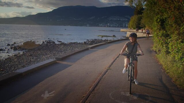 Happy woman biking along the seawall trail in stanley park, vancouver, british columbia