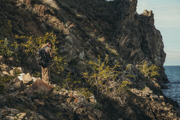a man with a fishing rod stands on a rocky shore against the backdrop of rocks