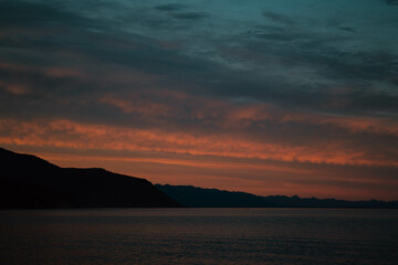fiery sunset over the sea surface, turquoise sky with clouds