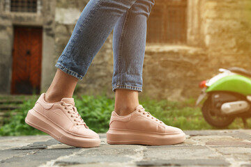 Woman in stylish sneakers walking on city street, closeup