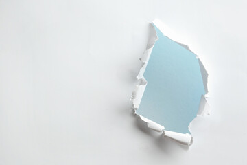 Hole in white paper on light background, space for text