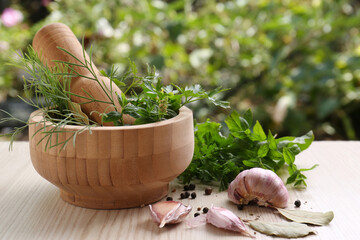 Mortar with pestle and different ingredients on wooden table outdoors