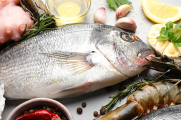 Fresh raw dorado fish, shrimps, octopus and lemon on light grey table, closeup