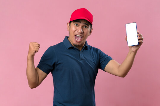 Portrait of a excited happy young delivery man showing display of mobile phone.