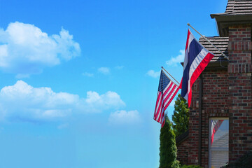 the flag of America attached to porch of house, is reflected in the window, the blue sky is white clouds. Place for text and editing