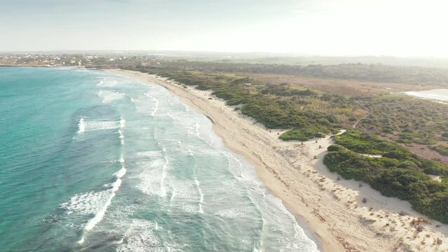 Crystal Blue Sea With Waves Splashing Onto Fine Sandy Beach In The Vendicari Nature Reserve, Sicily, Italy. aerial