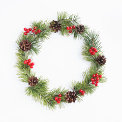 Fototapeta na wymiar Pine christmas wreath decorated with cones and red berry fruits on white background