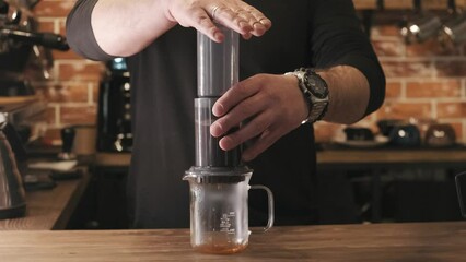 Barista making Aeropress coffee, press to device and coffee drops pours trought aeropress to teapot