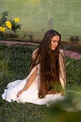 Obraz premium A girl with very long hair sits on the grass in a torpic landscape. White dress of the bride. Healthy hair. Women's beauty. Girl in the Maldives. Beautiful face.Natural beauty products for self-care