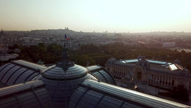 Beautiful cinematic shot of Grand Palais with shining glass rooftop of Petit palais at misty sunrise, captured by drone.