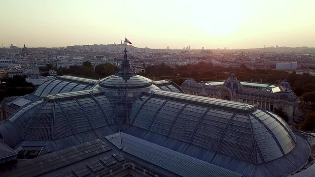Aerial tour of Grand palais in the morning with sun reflecting through glass windows, featuring Paris city in backdrop and beautiful Petit Palais