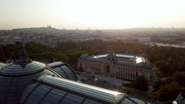 Aerial view of golden sun reflecting on beautiful glass rooftop edge of Grand Palais, a luxury tourist attraction in front of Petit Palais on Av. Winston Churchill, Montmarte, Paris City at distance