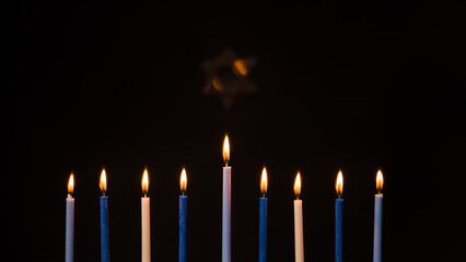 Menorah candles during Hanukkah with Star of David on a black background