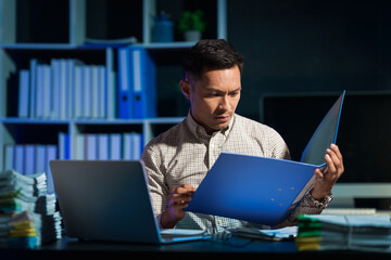 Overtime work concept, Handsome asian business man working late at night in office workplace.