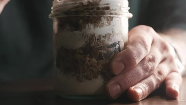 Hungry hipster man eating trifle dessert or granola in a glass