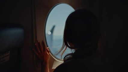 Girl on plane puts hand up to airplane window