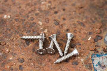 Tapping screws made of steel on steel rusty background, metal screw, iron screw, chrome screw, screws as a background, wood screw, concept industry. copy space for text.