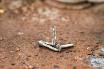 Tapping screws made of steel on steel rusty background, metal screw, iron screw, chrome screw, screws as a background, wood screw, concept industry. copy space for text.