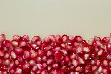 Ripe pomegranate seeds isolated on cream background.