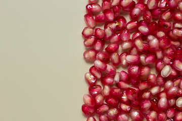 Ripe pomegranate seeds isolated on cream background.