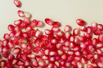 Ripe pomegranate seeds isolated on cream background.