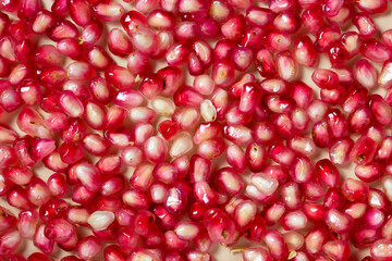 Ripe pomegranate seeds isolated on cream background.