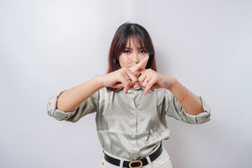 Beautiful Asian woman wearing sage green shirt with hand gesture pose rejection or prohibition with...