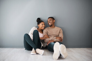 Homeowner, love and beginning with a black couple sitting together in their new home on a gray wall...
