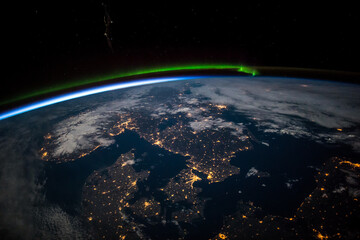 Aerial view from above Earth showing Scandinavia at night. Green aurora above the northern Baltic...