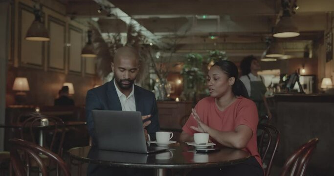 Two Businesspeople using Laptop and having a Meeting in a Restaurant
