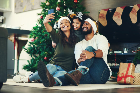 Christmas selfie, family and happy with holiday and celebration, mother with father and child smile holding smartphone. Christmas tree decoration, gifts and happiness in picture with happy family.