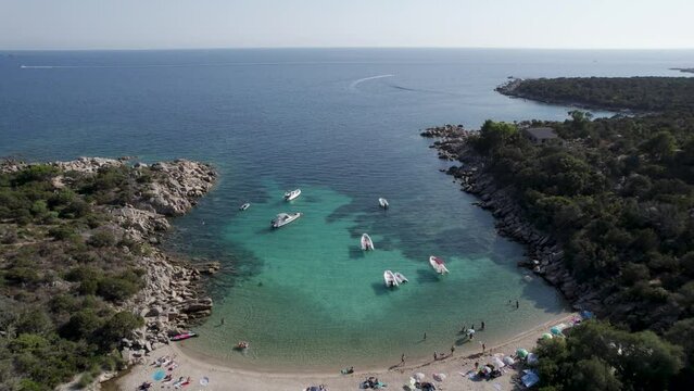 Las Cricas cove in Tizzano Beach Corsica Island Mediterranean Sea with boats and bathing tourists, Aerial tilt up reveal shot