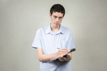Young man with clipboard on light background