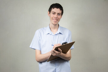 Young man with clipboard on light background