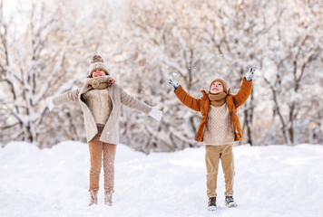 Happy little kids brother and sister rejoicing first snow in snowy winter park