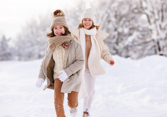 Happy active family mother and little daughter have fun in winter park, play catch-up in snowy day