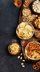 Assortment of salty snacks on dark background.