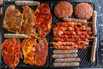 Raw beef and pork meat, sausages on BBQ grill. Top view.