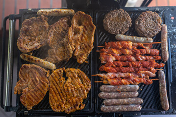 Delicious beef and pork meat, sausages on BBQ grill. Top view.