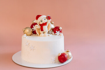 White Christmas cake with caramel bunny and balls against pink background.