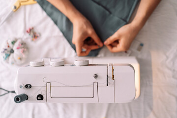 Lady fixes fabric with needles in front of a sewing machine.