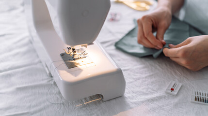 Lady fixes fabric with needles in front of a sewing machine.