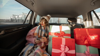 Woman in car with Christmas presents - obrazy, fototapety, plakaty