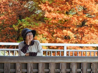 紅葉を背景にログハウスでくつろぐ高齢日本人女性