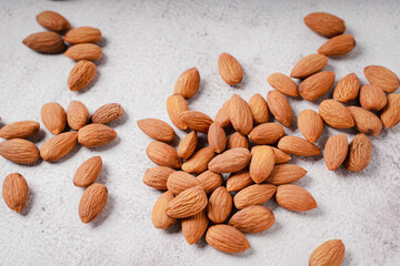 Almonds in white porcelain bowl on white table. Almond concept with copyspace.