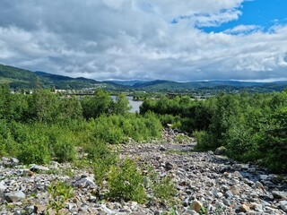 river in the mountains with the city of Mosjøen in the far background