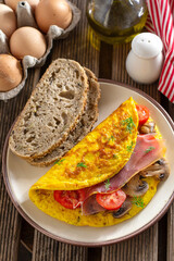 Browned omelette omelet stuffed with ham, mushrooms and tomatoes