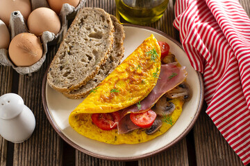 Browned omelette omelet stuffed with ham, mushrooms and tomatoes