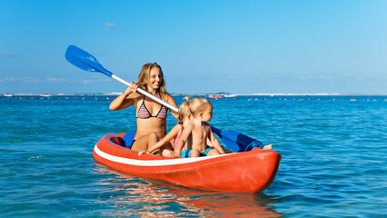 Happy family - young mother, children have fun on boat walk. Woman and child paddling on kayak. Travel lifestyle, parents with kids recreational activity, watersports on summer sea beach vacation.
