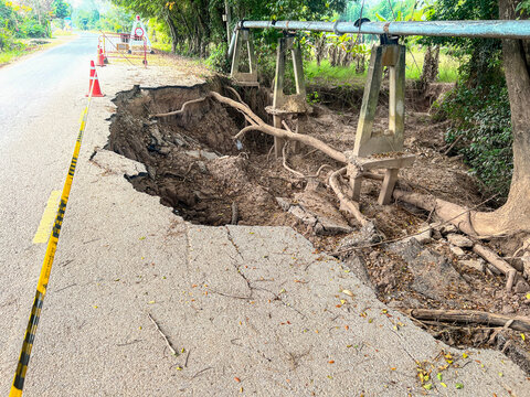 Asphalt road collapsed and cracks in the roadside, Road landslide subside with road cone caused by river erosion